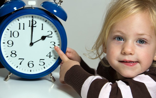 Kind zeigt auf eine Uhr
