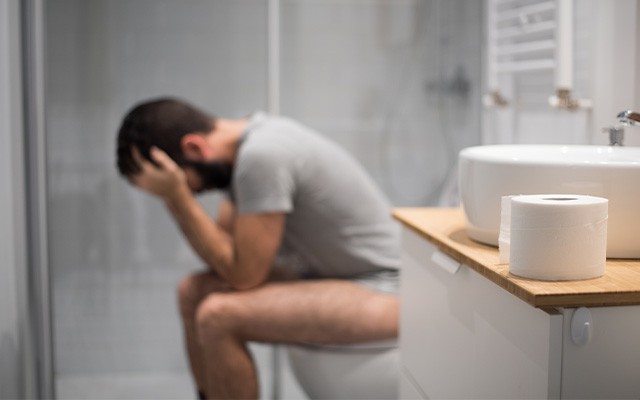 Mann sitzt auf der Toilette