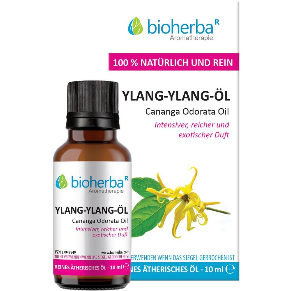 Eine Flasche Ylang-Ylang-Öl mit buntem Etikett und Blume daneben.